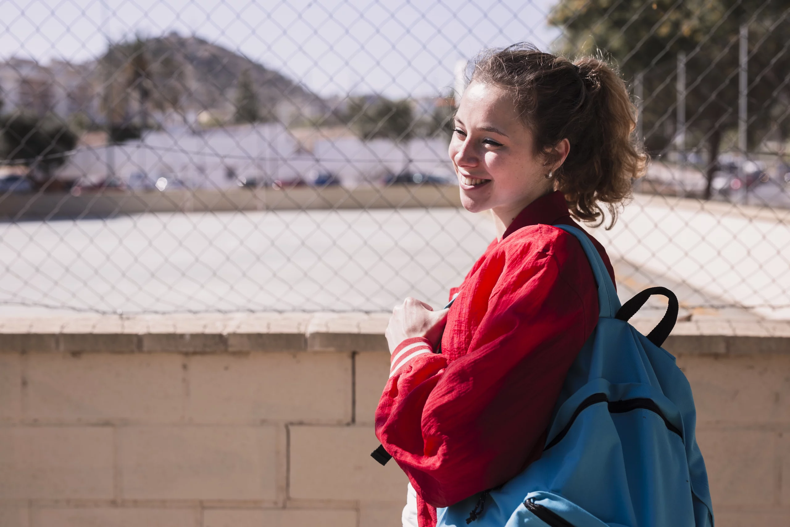 Jeune femme de face, souriante, portant son sac à dos pour sa rentrée scolaire.