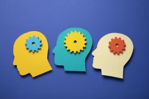 Illustration sobre de trois têtes humaines colorées avec des engrenages à l'intérieur, symbolisant le fonctionnement de la mémoire et de la pensée.