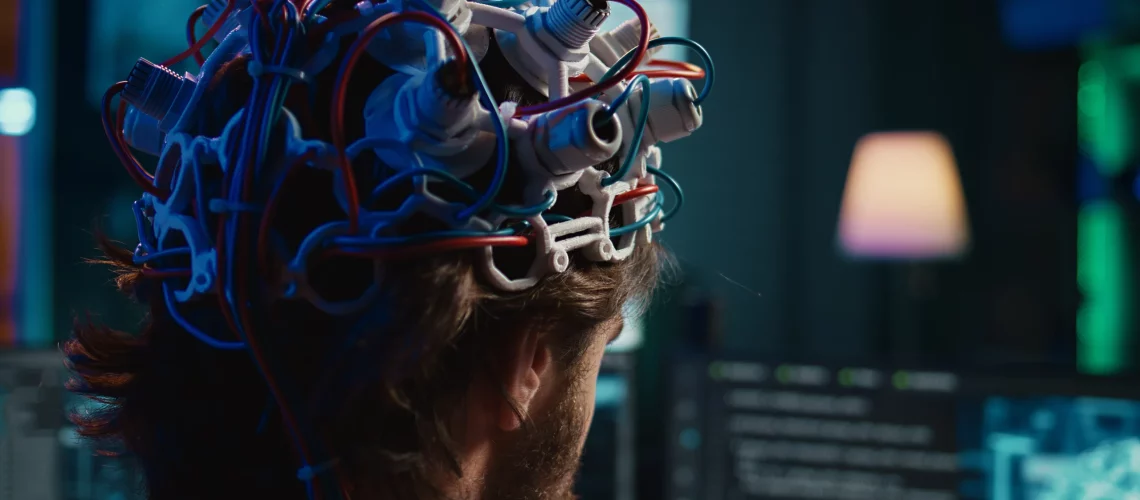 Personne de dos portant un casque avec des électrodes avec de nombreux câbles colorés, illustrant la neuroéducation et l'étude du cerveau.